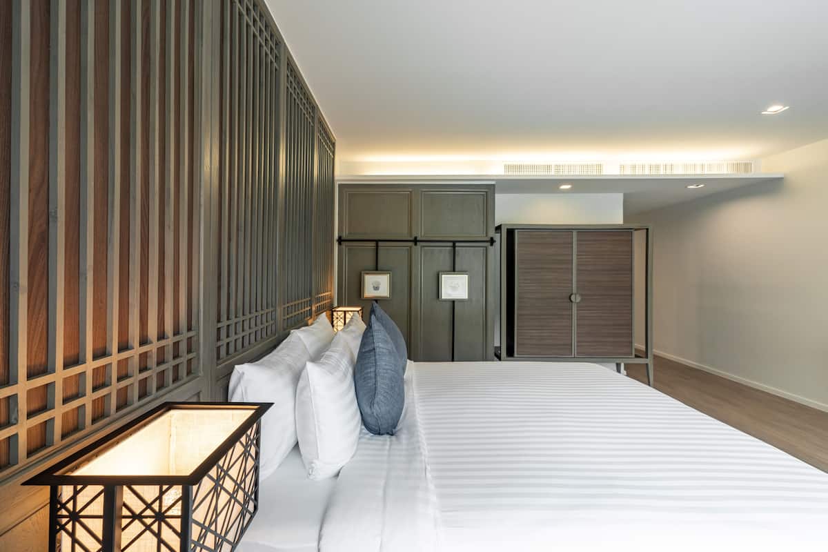 A bedroom with a bed, pillows, a bedside table, a wardrobe, and a mirror.