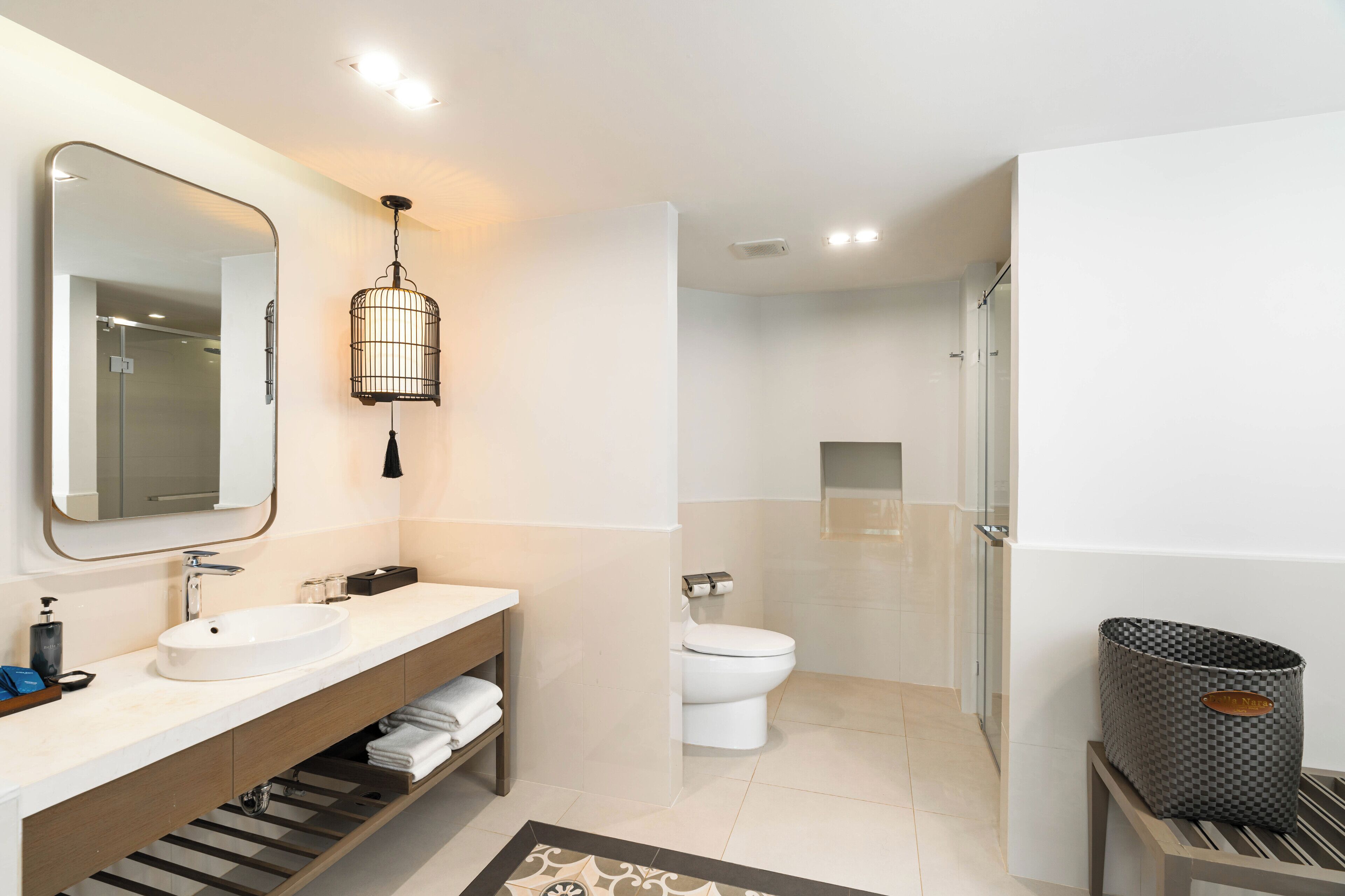 Un baño moderno con un espejo grande, dos lavamanos, un inodoro y una ducha.