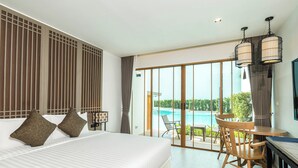 A hotel room with a large bed, a dining table with chairs, and a view of a swimming pool. - Bella Nara Phuket Naiyang Beach (Sa Khu)
