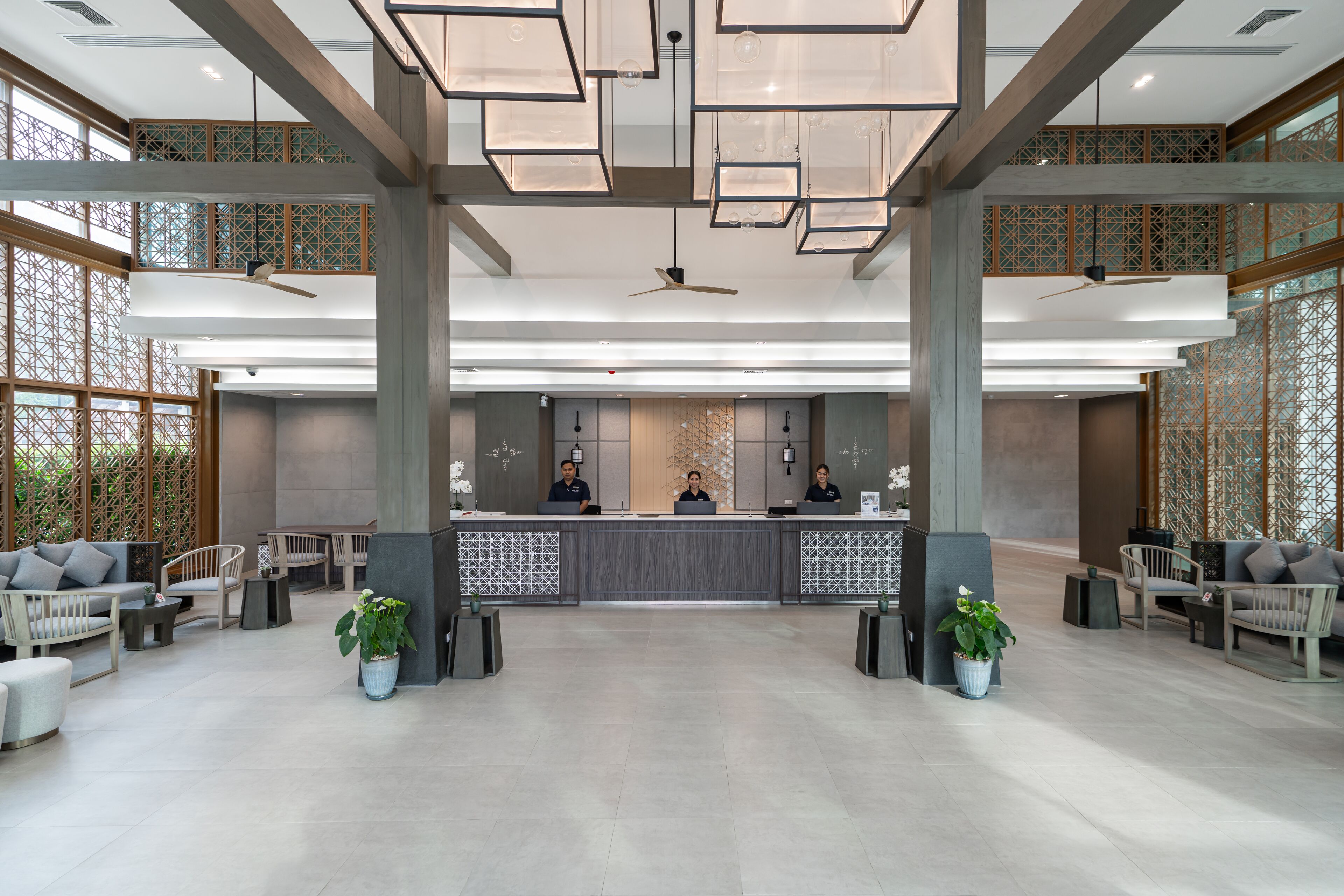 Un lobby amplio con una recepción, zona de estar y paneles decorativos en el techo.