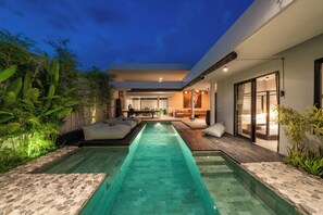 Uma área de piscina moderna ao ar livre, com piscina cristalina, deck de madeira e áreas de estar.