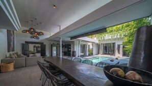 A modern outdoor living area with a pool, bar, and seating. - Villa Wiraja 2 (Canggu)