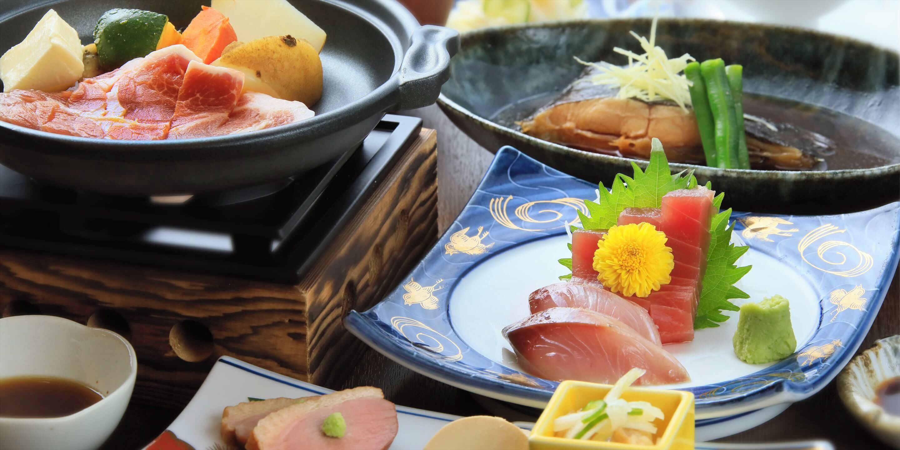 Una selezione di piatti tra cui sashimi, verdure e una pentola calda.