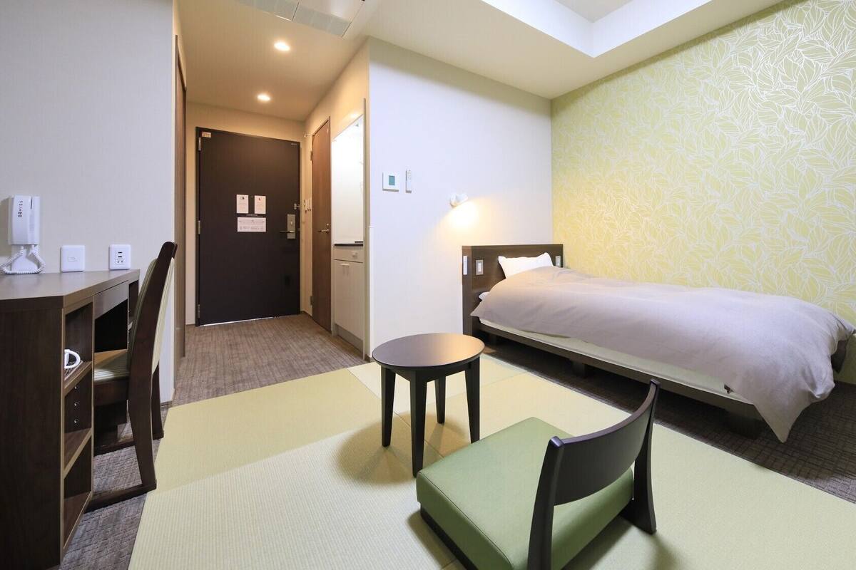 Ein Hotelzimmer mit Bett, Schreibtisch, Stuhl, kleinem Tisch und einer Couch.