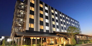 Um hotel moderno com estrutura em vários andares, área de entrada coberta e fachada bem iluminada.