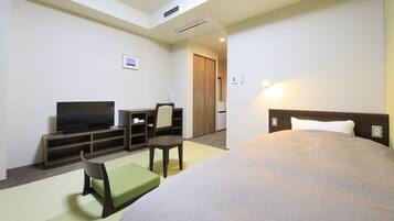 Une chambre d’hôtel comprenant un lit, une télévision, une petite table, une chaise et un canapé.