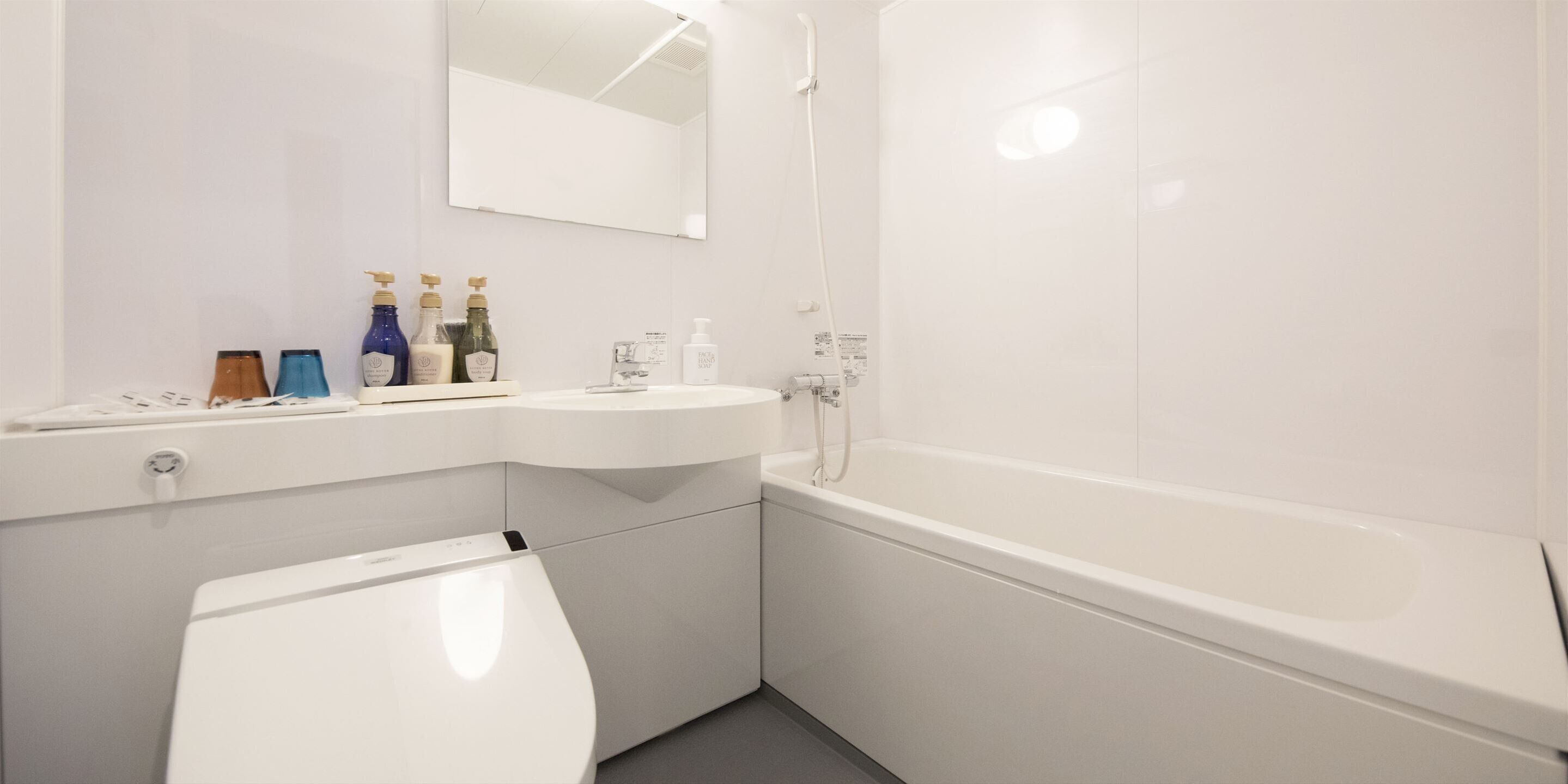 Une salle de bain moderne avec des toilettes, un lavabo et une baignoire, le tout de couleur blanche.