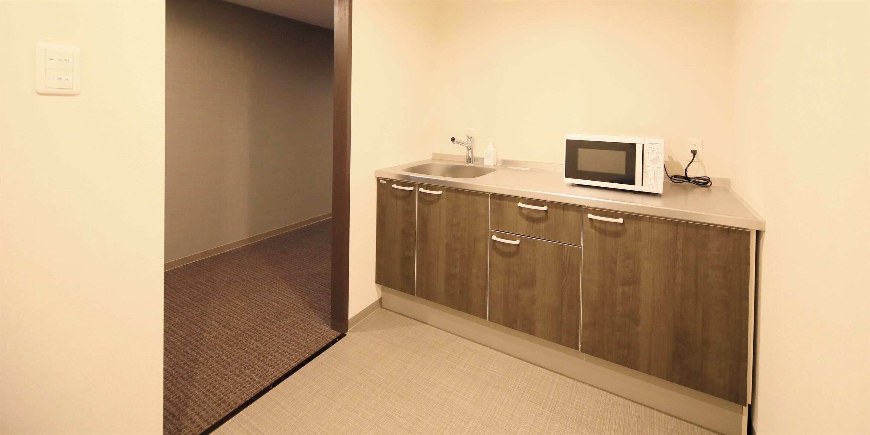 Una kitchenette compacta con microondas, pileta y alacena.