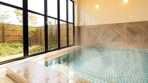 Une piscine dont le fond est recouvert de carrelage, avec vue sur une clôture en bambou à l’extérieur.
