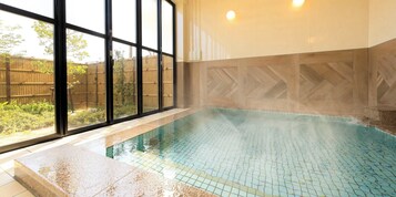 Piscina com piso de azulejos e vista para uma cerca de bambu.