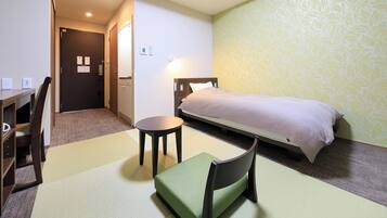 Ein Hotelzimmer mit Bett, Schreibtisch, Stuhl und kleinem Tisch.