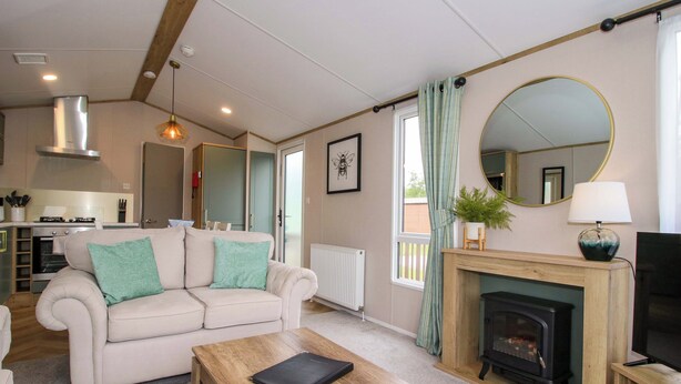 A living room with a sofa, coffee table, fireplace, and a kitchen in the background. - Owl (Leominster)