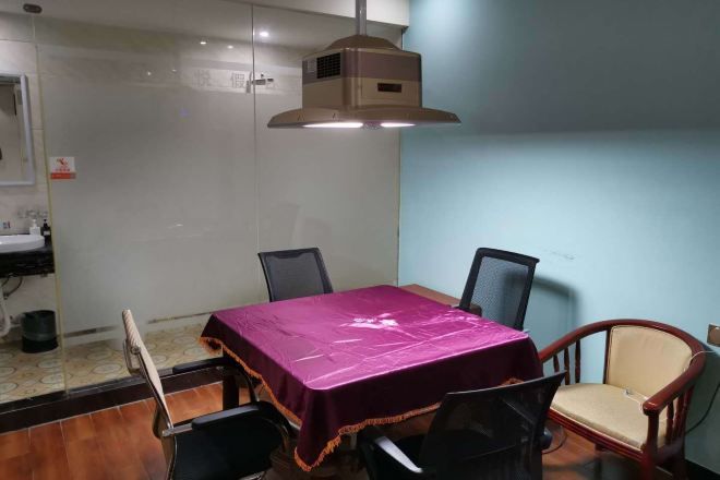 A conference room with a table, chairs, and a ceiling-mounted air conditioning unit.