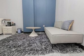 A modern room with a white sofa, a small round table, and a grey shag rug. - junyue hotel (Fangchenggang)