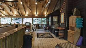 Interior de una cabaña de madera con barra, asientos y chimenea.