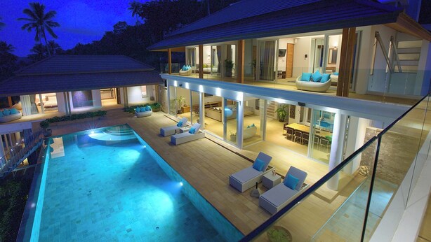 Una casa moderna a due piani con piscina, area relax esterna e ampie finestre.