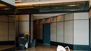 Un área de recepción moderna con un mostrador de recepción, un cubo de basura y una puerta al fondo.