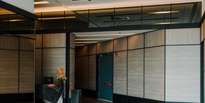 A modern reception area with a reception desk, a trash bin, and a door in the background. - Datum Jelatek by Plush (Ampang)