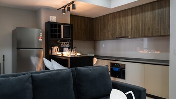A modern kitchen with wooden cabinets, a built-in oven, and a dining area with a black table and chairs.