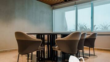 A modern interior with a conference table surrounded by four chairs, large windows, and a logo for Plush Services.