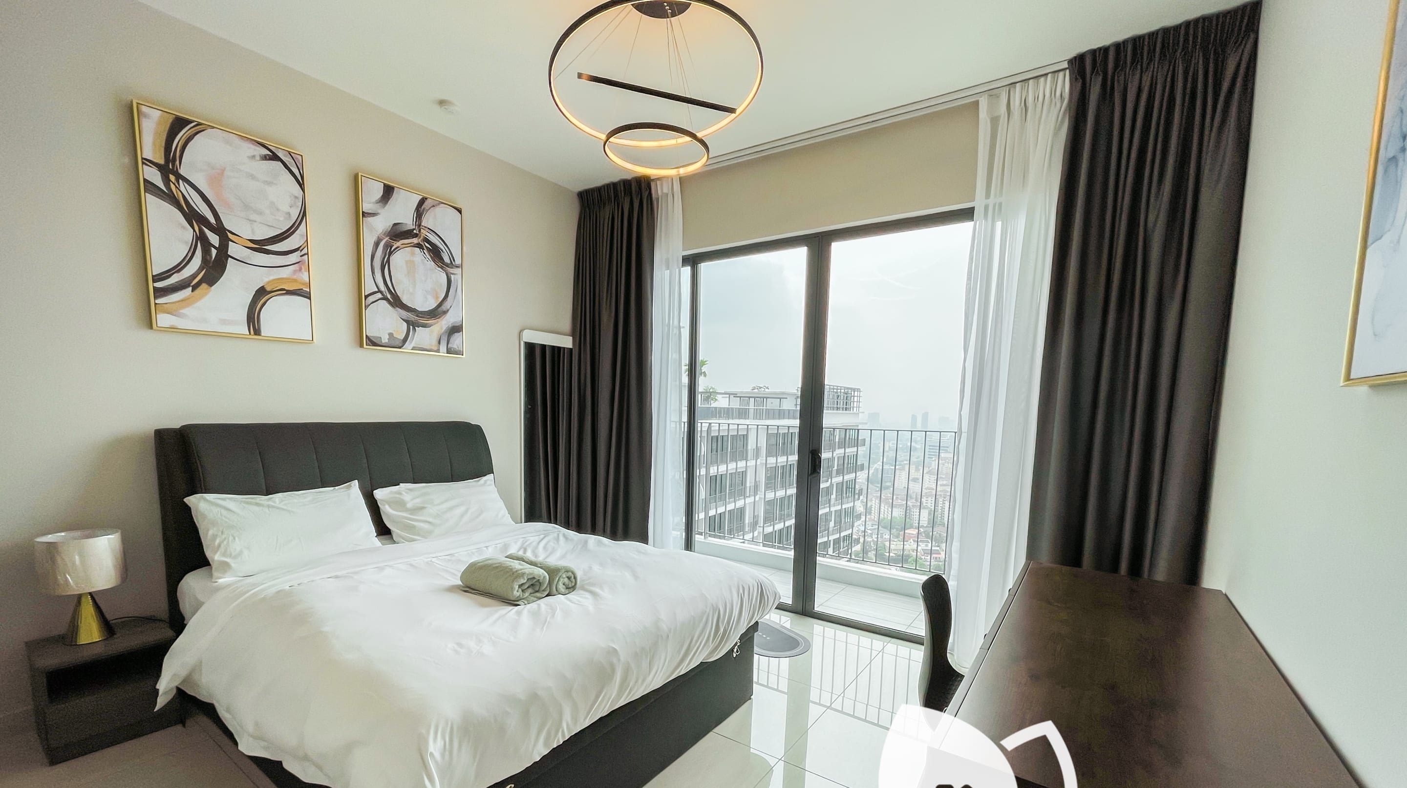 A modern hotel room with a large bed, a desk, and a view of the city.