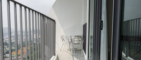 Varanda com vista para a paisagem urbana, uma mesa e duas cadeiras.