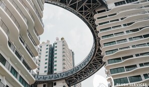 A modern high-rise building with a curved bridge connecting two sections. - Datum Jelatek by Plush (Ampang)