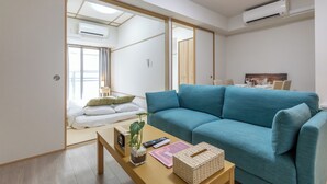 A modern living room with a blue sofa, a wooden coffee table, and a small plant. - H2H SHINSAIBASHI I (Osaka)
