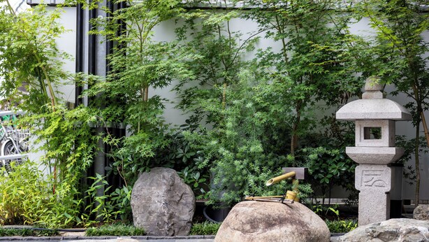 A serene garden with large rocks, a traditional Japanese stone lantern, and lush greenery. - H2H SHINSAIBASHI I (Osaka)