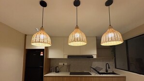 Une cuisine moderne avec trois suspensions en osier, un réfrigérateur noir et un dosseret carrelé.