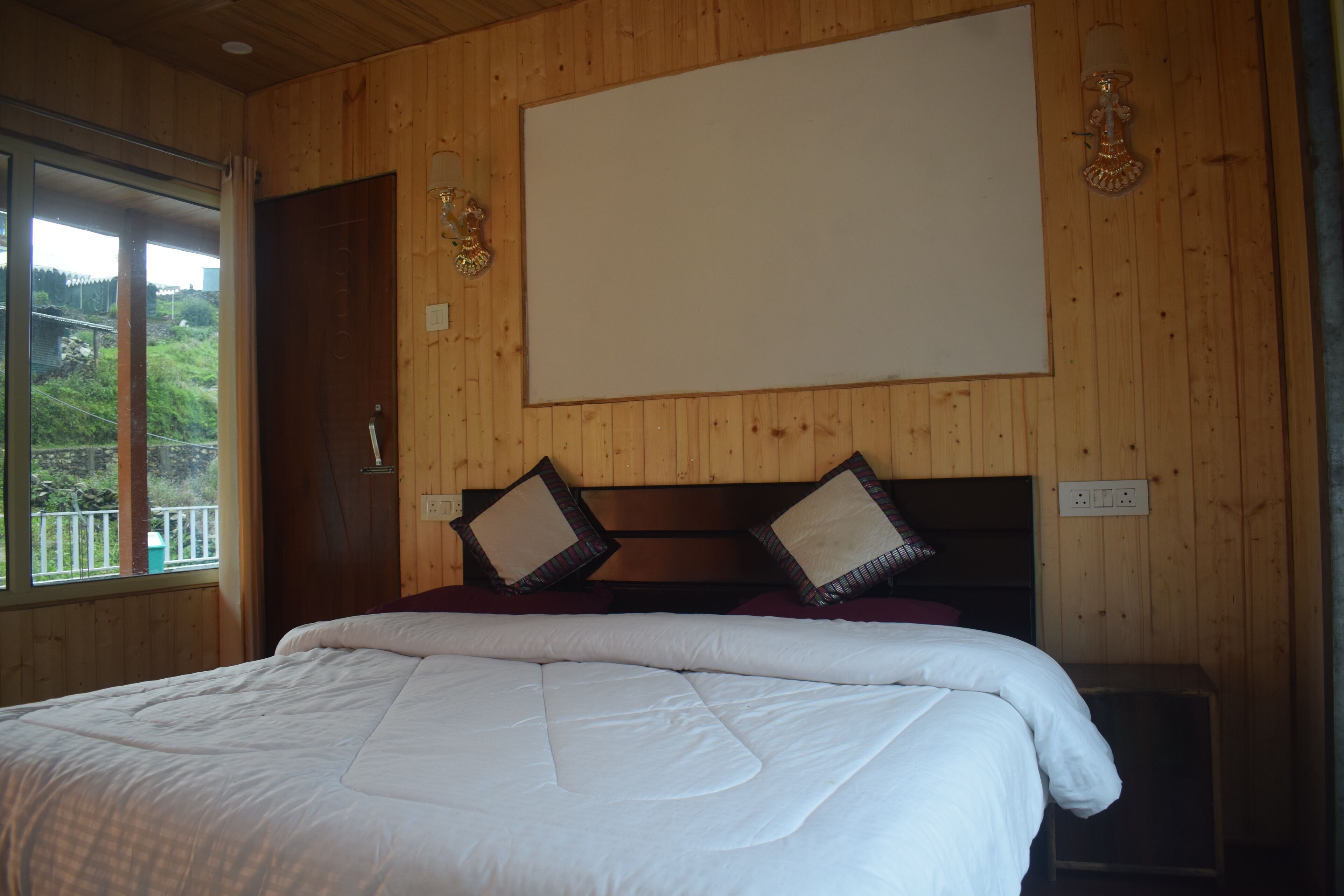 A wooden-paneled room with a bed, a large window, and a whiteboard on the wall.