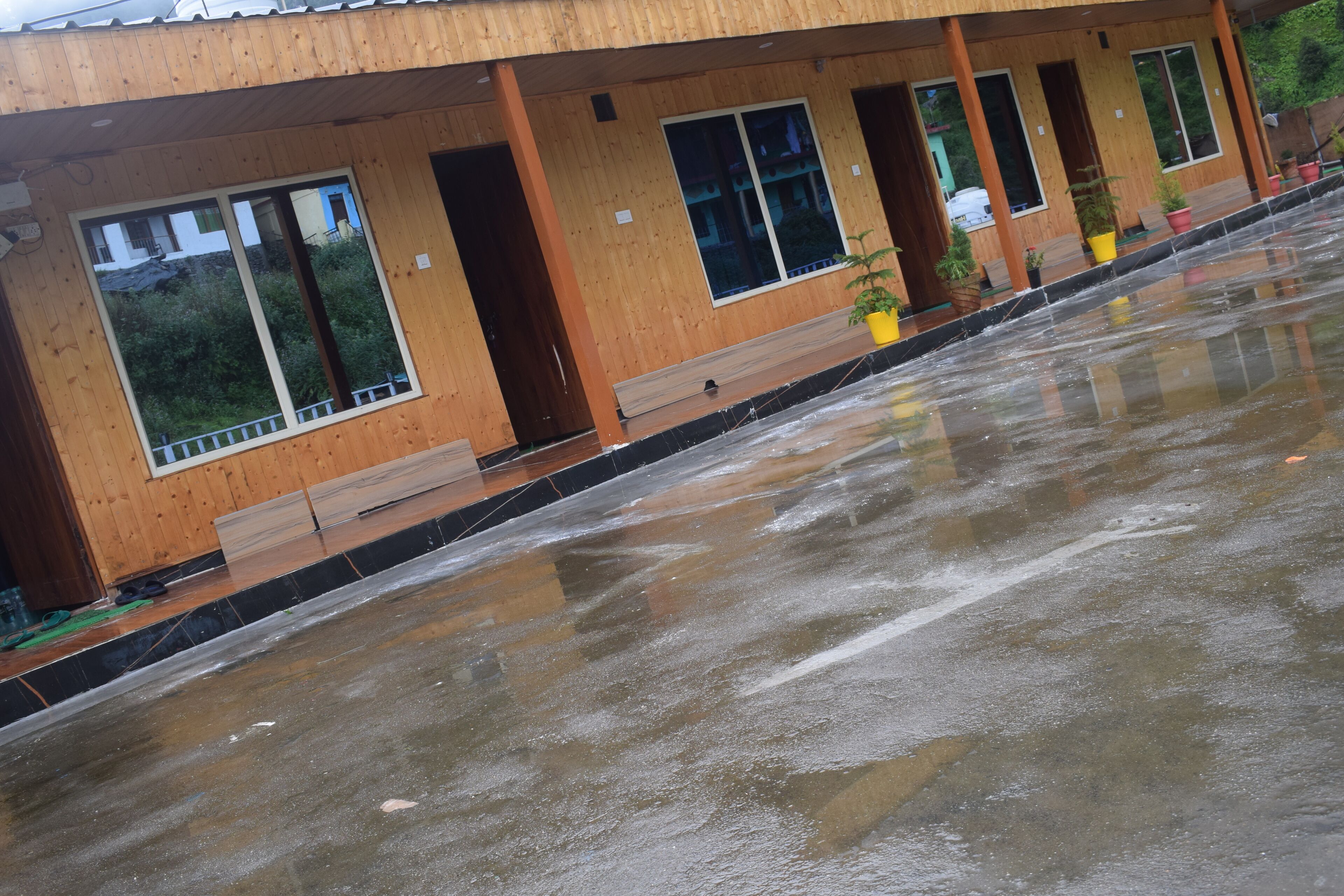 Un edificio de madera con ventanas grandes y suelo mojado, probablemente por la lluvia.