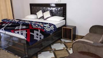 Una cama con un edredón estampado, cabecera y mesita de noche.