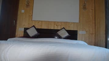A hotel room with a wooden wall, a bed with white bedding, and two decorative wall sconces.