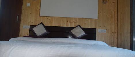 A hotel room with a wooden wall, a bed with white bedding, and two decorative wall sconces.