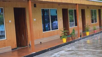 A row of wooden cabins with large windows and potted plants.