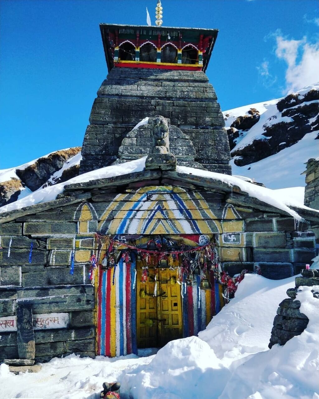 A snow-covered building with a colorful entrance and a small tower on top.