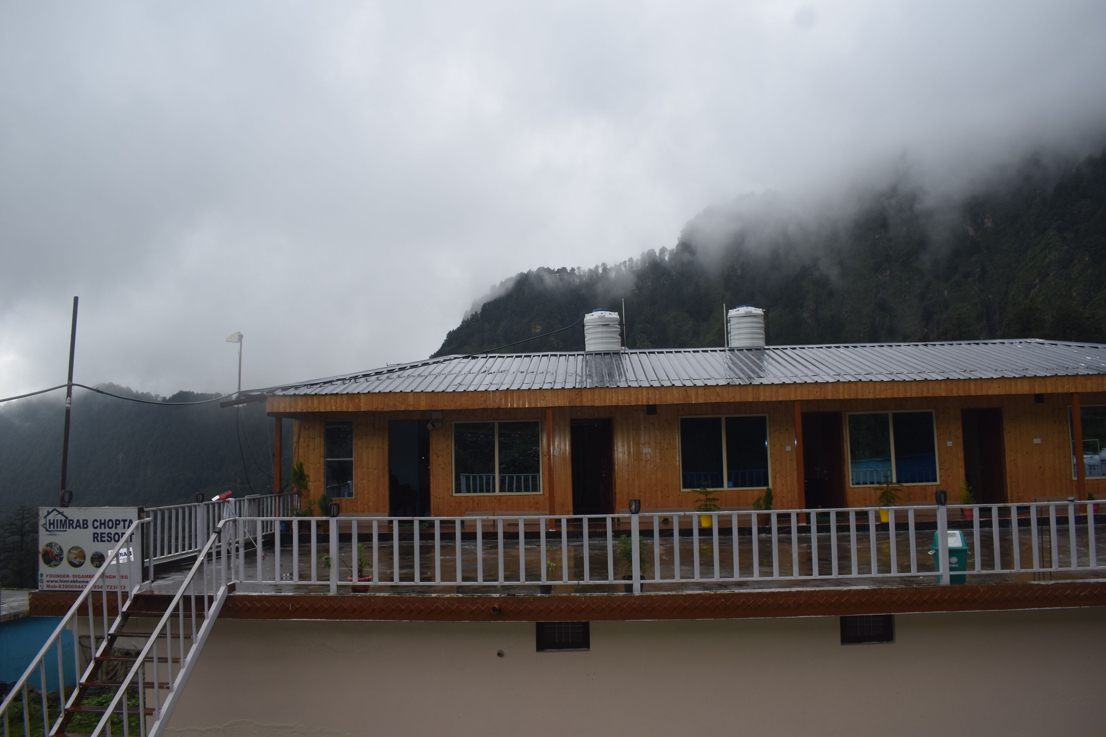 A building with a metal roof and white railings, surrounded by a mountainous landscape.