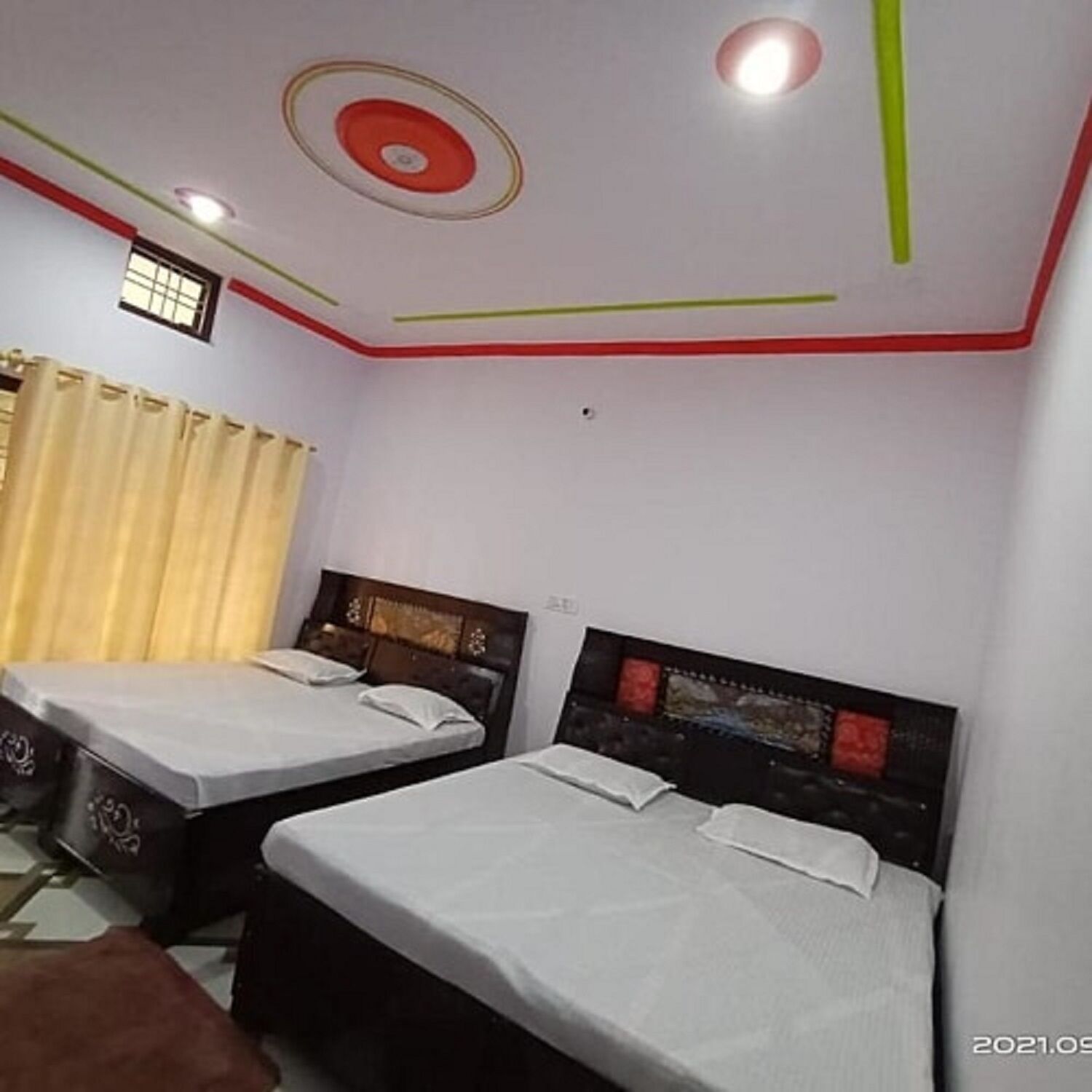 Une chambre d’hôtel avec deux lits simples, une petite fenêtre et un rideau.