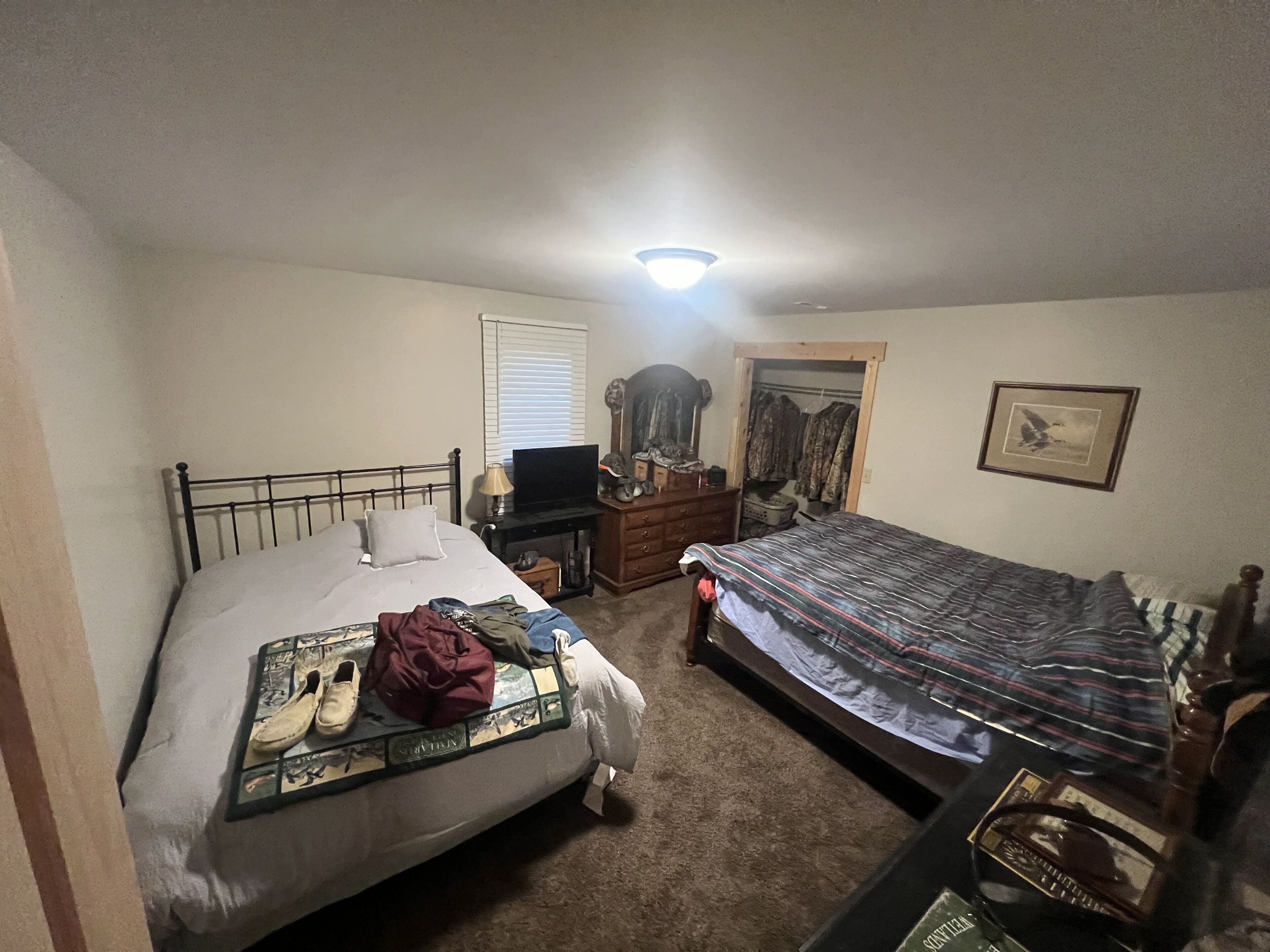 A bedroom with a bed, a dresser, a desk, a closet, and a ceiling light.