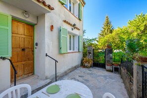 A courtyard with a table set for dining, a wooden door, and a stone wall.