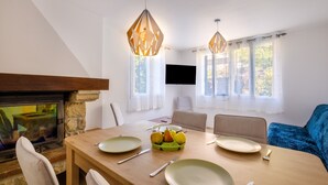 A dining area with a wooden table, chairs, a fruit bowl, and hanging pendant lights. - Holiday Home 'Jolie Maison' with Wi-Fi (Lucéram)