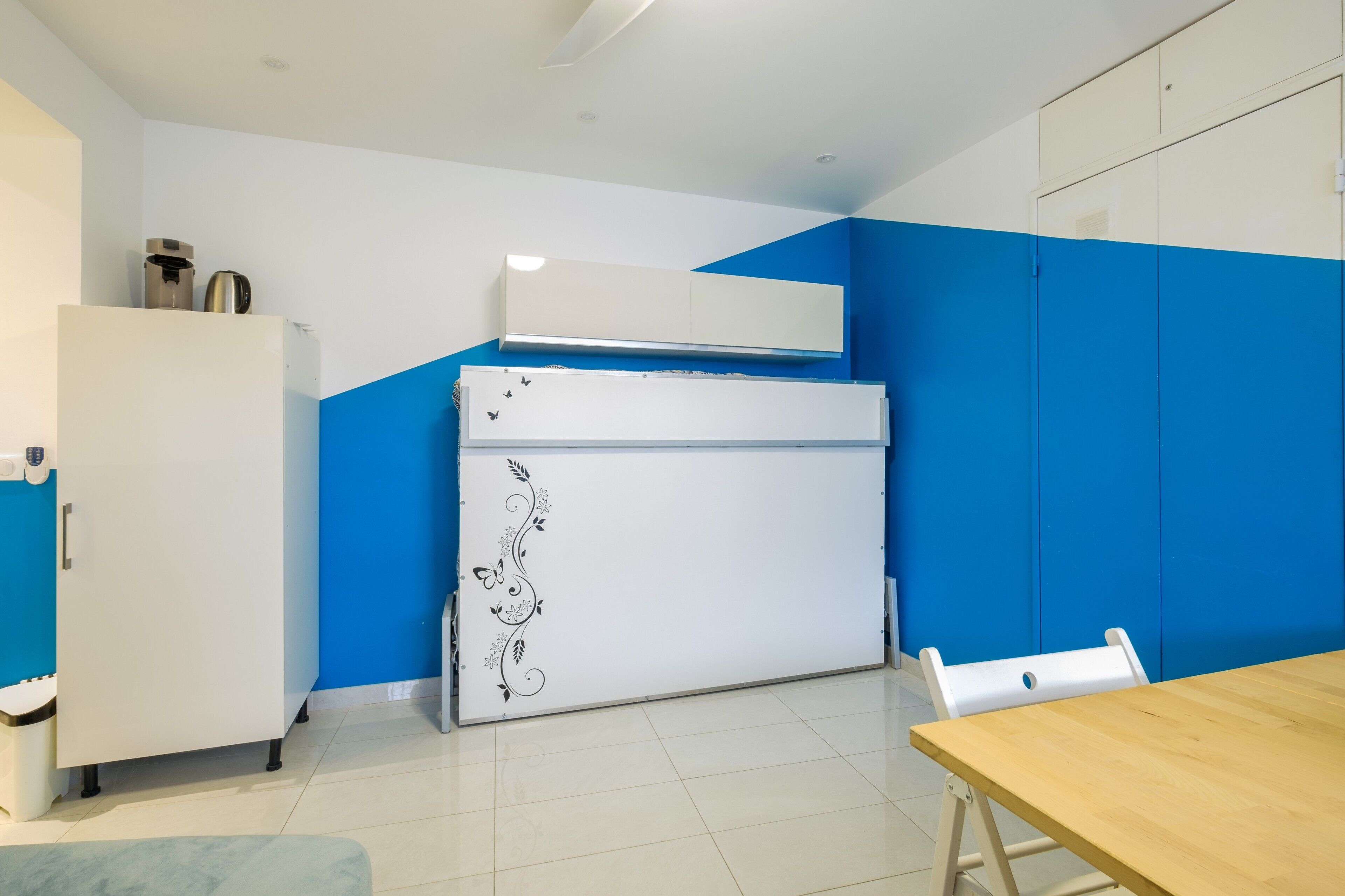 Een keuken met een witte koelkast, een wit fornuis en een blauwe wand.