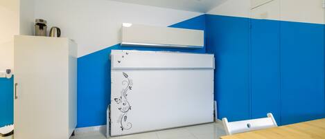 Een keuken met een witte koelkast, een wit fornuis en een blauwe wand.