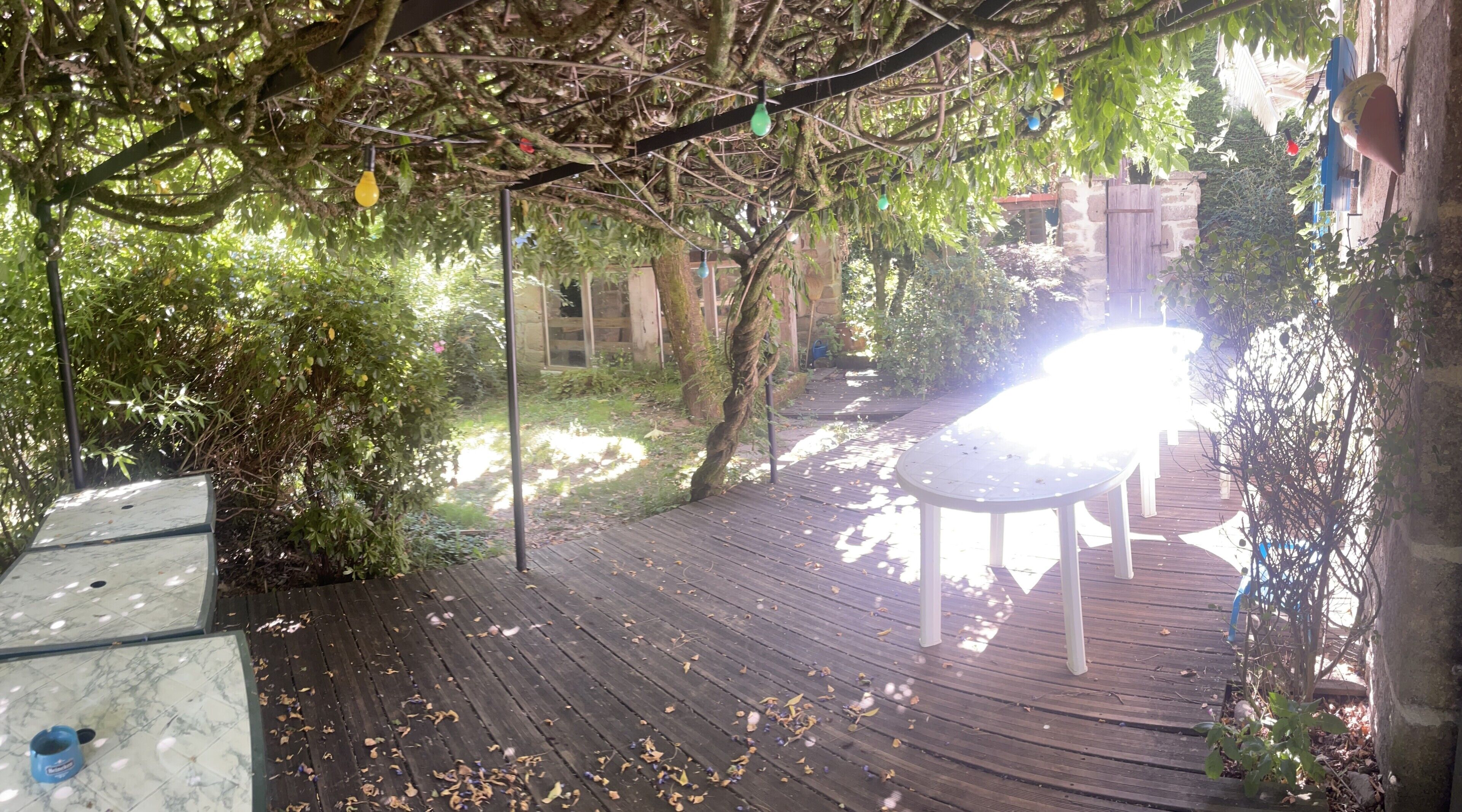 A wooden deck with a table and chairs, surrounded by trees and greenery.