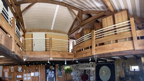 A barn with wooden beams, a loft area, and a stone wall.