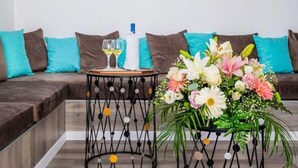A modern living room with a sectional sofa, two black metal side tables with decorative elements, a vase of flowers, and two framed artworks on the wall. - Holiday Home "Sweet Home Madeira" with Sea View, Private Terrace & Wi-Fi (Camacha)
