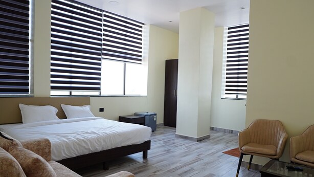 Habitación de hotel con una cama grande, un escritorio, dos sillas y un armario.