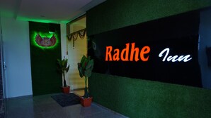 Entrada de un hotel con un cartel que dice "Radhe Inn" y una decoración de pavo real.
