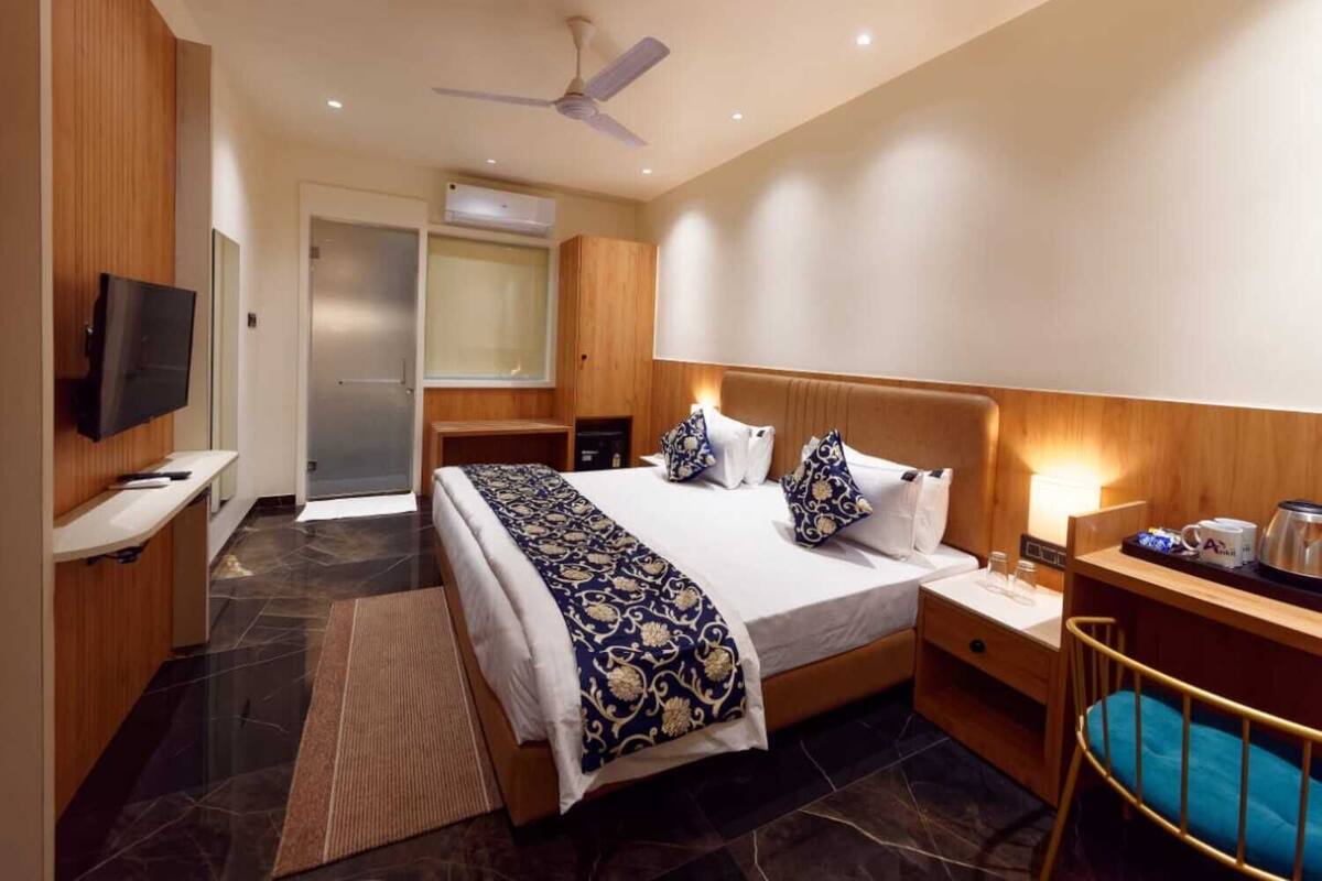 A hotel room with a bed, a TV, a desk, a chair, and a ceiling fan.